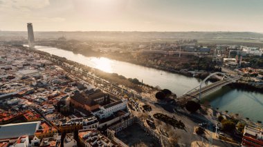 Barqueta Köprüsü 'nün Sevilla, Endülüs, İspanya' daki Guadalquivir Nehri üzerindeki havadan görüntüsü. Seville 'de gün batımı, şehir merkezi ve Sevilla kulesi. Şehre giriş, ulaşım istasyonları. Sevilla' da trafik..