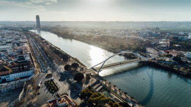 Barqueta Köprüsü 'nün Sevilla, Endülüs, İspanya' daki Guadalquivir Nehri üzerindeki havadan görüntüsü. Seville 'de gün batımı, şehir merkezi ve Sevilla kulesi. Şehre giriş, ulaşım istasyonları. Sevilla' da trafik..