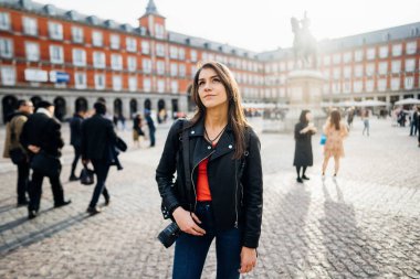 Madrid, İspanya 'da Plaza Major Meydanı' nda elinde kamera olan bir kadın turist. Genç kadın fotoğrafçı. Maddy 'nin mimarisi ve simgesi. Seyahat fotoğrafçılığı. Blogger yaşam tarzı.