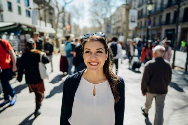 Barselona, İspanya 'da, La Rambla caddesinde gezen neşeli genç bir bayan turist. Barselona' nın ünlü alışveriş caddesinde yürüyor. Seyahatin tadını çıkarıyor. Bir Treveler kadınının gözlerinde neşe.