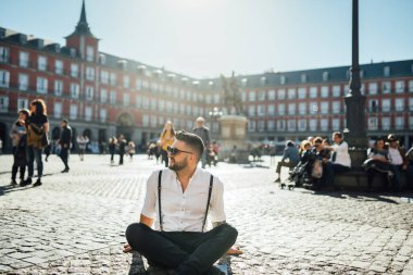 Etkileyici genç bir adam. Ünlü şehir ve mekanları ziyaret eden turist. Ünlü Plaza Mayor Meydanı 'nda neşeli erkek gezgin.