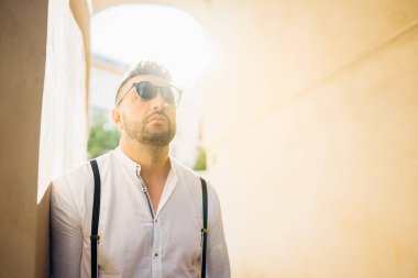 Gün batımında ayakta duran yuvarlak gözlüklü ve sakallı yakışıklı adam. Yakışıklı bir adamın portresi. Endülüs, İspanya 'ya gezi düzenleyen erkek turist..