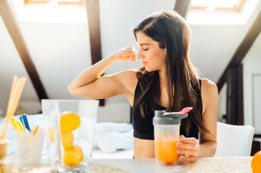 Evde portakal aromalı amino asit vitamin tozu içen kadın. Egzersiz sonrası Keto takviyesi. Kilo kaybı beslenme düzeni. Bağışıklık sistemi desteği.