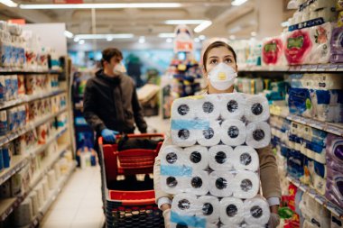 Maskeli ve eldivenli kadın teçhizat deposuna tuvalet kağıdı almak ve stoklamak için panik yapıyor. Patojen virüsü salgını için karantinaya hazırlanıyor. Covid-19 nedeniyle toplu temizlik malzemesi almaya hazırlanıyor..