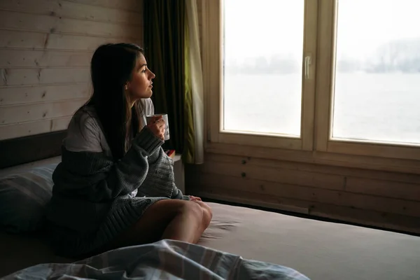 若い女性は自宅でコーヒー 紅茶を飲みに滞在します 窓を通して見て 一日を開始 朝の儀式 クアドライン自己分離の概念 — ストック写真