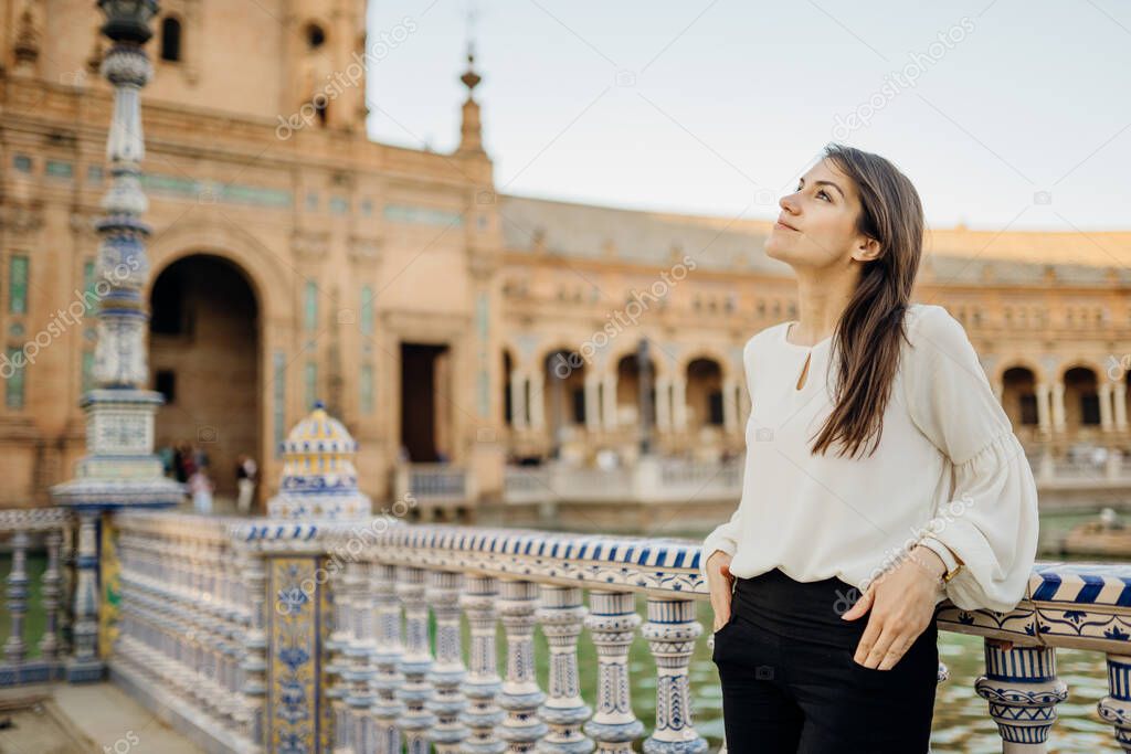 Young tourist woman looking over Plaza de Espana  in, Seville (Sevilla), Andalusia, Spain.Traveling to Spain.Sunset on Spain Square.Female  traveler visiting Spain,enjoying view,mindful walk.