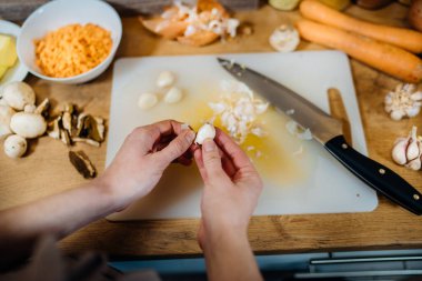 Taze sarımsak soymak. Sarımsaklı yemek pişirmek için malzemeler. Güçlü bağışıklık sistemi için sağlıklı yiyecekler. Tahtada sarımsak pişiriyorum. Kadın sarımsak soyuyor. Taze baharat kullanıyor.