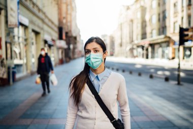 Şüpheli bir genç yetişkin pandemic sırasında kamusal alanda yürüyor. COVID-19 'un etkisi. Koruyucu tedbir, maske takmak. Kılavuzlara saygı. Boş sokaklar.