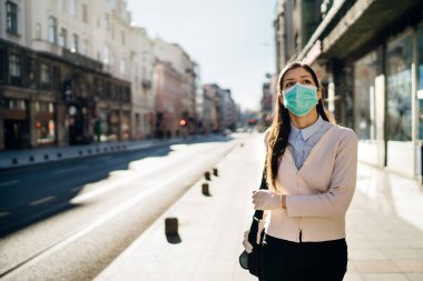 Endişeli kadın pandemic sırasında halka açık alanda yürüyor. COVID-19 'un etkisi. Koruyucu tedbir, maske takma. Kılavuza saygı. Boş sokaklar. Koronavirüs korkusu.