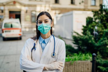 Cephedeki cesur iyimser sağlık görevlisi, enfeksiyon kapmış hastalarla birlikte izolasyon hastanesinde çalışıyor. Covid-19 acil servis triyaj doktoru koruyucu gözlüklü / maskeli. Koronavirüsle savaşıyor.