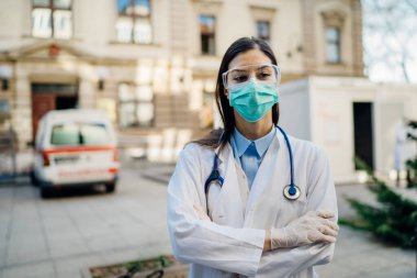 Cephedeki cesur iyimser sağlık görevlisi, enfeksiyon kapmış hastalarla birlikte izolasyon hastanesinde çalışıyor. Covid-19 acil servis triyaj doktoru koruyucu gözlüklü / maskeli. Koronavirüsle savaşıyor.