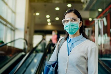 Coronavirus covid-19 salgını sırasında işe giderken dikkatli ol. Ofis ortamında korunan koruyucu gözlüklü ve maskeli iş kadını. Profesyoneller için hijyenik temizlik standartları.