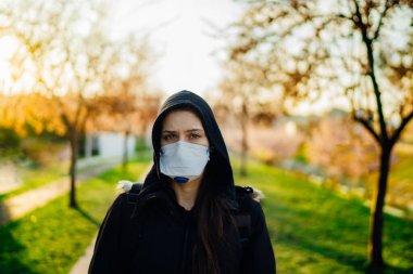 Bahar doğasında hastalığa yakalanmamak için N95 maskesi takan depresif bir insan. Coronavirüs salgını. Panik ve korku. COVID-19 'un duygusal etkisi.