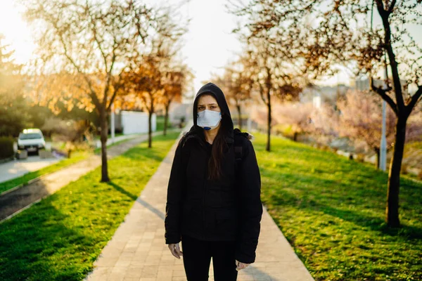 Depressed scared person wearing a protective N95 mask to prevent contagious disease spread in spring nature.Coronavirus pandemic life.Panic and fear of infection.Emotional effect of the COVID-19.