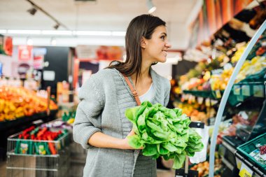 Genç bir kadın marketten taze sebze alıyor. Sürdürülebilir organik sebzeler alıyor. Doğal vitamin ve mineral kaynağı. Vegan / vejetaryen diyeti.