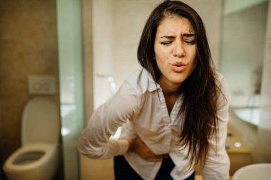 Şiddetli karın ağrısı çeken genç bir kadın. Gastrointestinal otoimmün hastalık. Dismenoroz / endometriyozis. Gastrointestinal sorun.