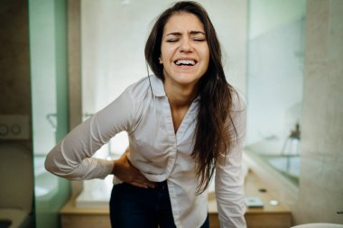 Şiddetli karın ağrısı çeken genç bir kadın. Gastrointestinal otoimmün hastalık. Dysmenorrhea / endometriyozis. Jinekolojik sorun.