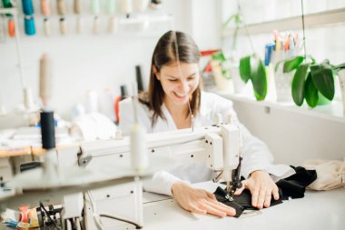 Dikiş makinesinde çalışan heyecanlı yaratıcı terzi. El yapımı koruyucu pamuk maskesi yapımı. DIY projesi, dikiş makinesi dikmeyi öğrenme. Kurs dikme hobisi. Giysi endüstrisinde mutlu terzi.