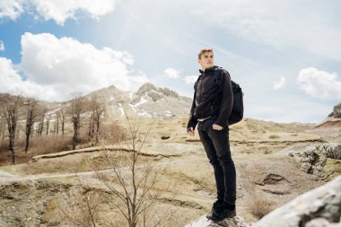 Adrenalin dağının tadını çıkaran genç bir gezgin. Aktif yürüyüş tatili. Dağ tepesine tırmanıyor. Doğada macera aktivitesi.
