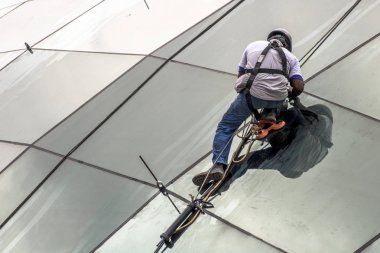 Sao Paulo, Brazil, January 02, 2017. Worker installs the glass plates on the roof of the Borba Gato station of line 5 lilac of the subway. clipart