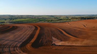 Aerial view of farmer plows with his tractor on his farm for peanuts planting in the rural area