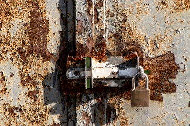 Padlock closing a rusty iron gate