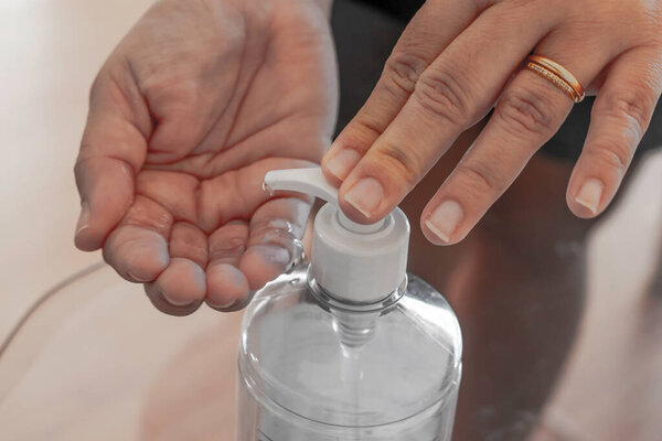 Hand sanitizer woman applying sanitizing gel liquid rubbing hands clean personal hygiene coronavirus pervention at home. Sanitiser bottle.