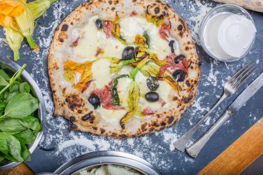 Kara tahta üzerinde mozzarella, salam, ricotta ve kabak çiçekleri ile geleneksel İtalyan pizza