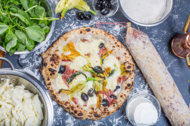 Kara tahta üzerinde mozzarella, salam, ricotta ve kabak çiçekleri ile geleneksel İtalyan pizza