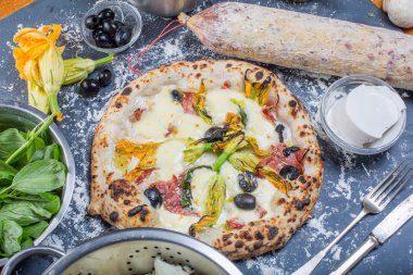 Kara tahta üzerinde mozzarella, salam, ricotta ve kabak çiçekleri ile geleneksel İtalyan pizza