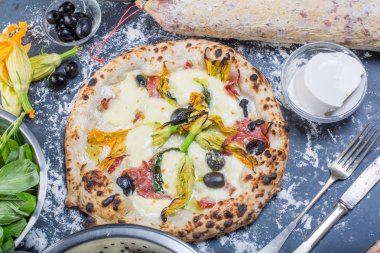 Kara tahta üzerinde mozzarella, salam, ricotta ve kabak çiçekleri ile geleneksel İtalyan pizza