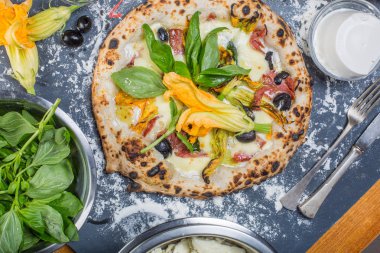 Kara tahta üzerinde mozzarella, salam, ricotta ve kabak çiçekleri ile geleneksel İtalyan pizza