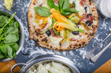 Kara tahta üzerinde mozzarella, salam, ricotta ve kabak çiçekleri ile geleneksel İtalyan pizza