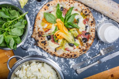 Kara tahta üzerinde mozzarella, salam, ricotta ve kabak çiçekleri ile geleneksel İtalyan pizza