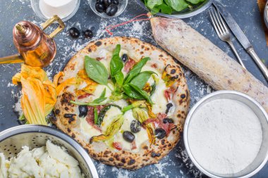 Kara tahta üzerinde mozzarella, salam, ricotta ve kabak çiçekleri ile geleneksel İtalyan pizza