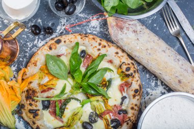 Kara tahta üzerinde mozzarella, salam, ricotta ve kabak çiçekleri ile geleneksel İtalyan pizza