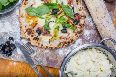 Kara tahta üzerinde mozzarella, salam, ricotta ve kabak çiçekleri ile geleneksel İtalyan pizza