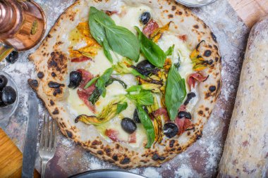 Kara tahta üzerinde mozzarella, salam, ricotta ve kabak çiçekleri ile geleneksel İtalyan pizza