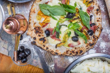 Kara tahta üzerinde mozzarella, salam, ricotta ve kabak çiçekleri ile geleneksel İtalyan pizza