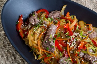 Sığır kesim, sebze ve siyah bir tabak spagetti yakın çekim