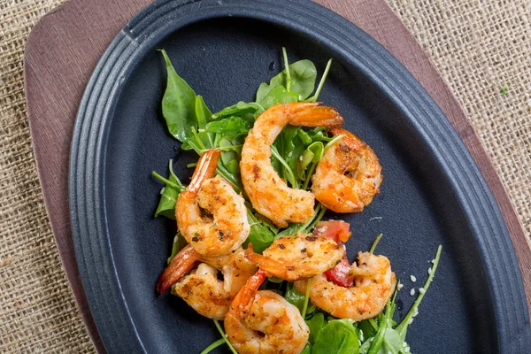 Close-up met vers gebakken shrimps met rucola op een zwarte plaat — Stockfoto