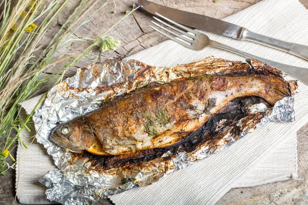 Bir alüminyum folyo üzerinde ızgara bütün alabalık 