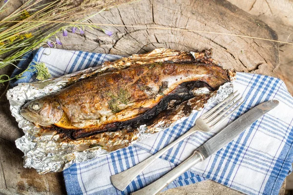 Bir alüminyum folyo üzerinde ızgara bütün alabalık 