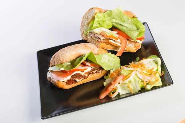 Сэндвич с сэндвичем и салатом на черной тарелке — стоковое фото