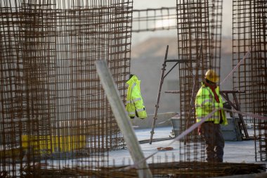 İnşaat alanında çelik çerçevelerde çalışan bir adam.