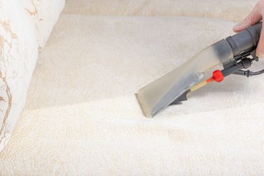 Kuru temizlemeci çalışanı mobilyalardaki toprağı temizliyor, yakın plan, profesyonel ekipmanla elektrikli kanepeyi temizliyor.