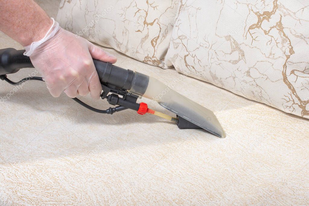 Dry cleaner's man employee removing dirt from furniture in flat, closeup, vacuum clean sofa with professional equipment