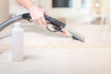 Kuru temizlemeci çalışanı mobilyalardaki toprağı temizliyor, yakın plan, profesyonel ekipmanla elektrikli kanepeyi temizliyor.
