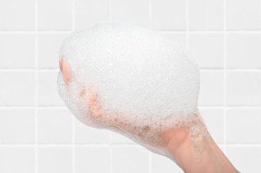 Banyo arka planında kadın eli olan sabun ve köpük. Ellerimi ve vücudumu yıkıyorum.