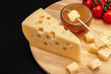 Sarı Maasdam peyniri, delikli üçgen peynir, ballı fincan tabağı, domates ahşap, siyah kayrak zemin